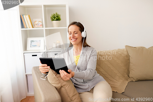 Image of happy woman with tablet pc and headphones at home