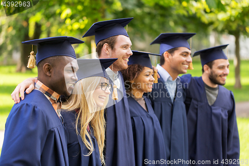 Image of happy students or bachelors in mortar boards