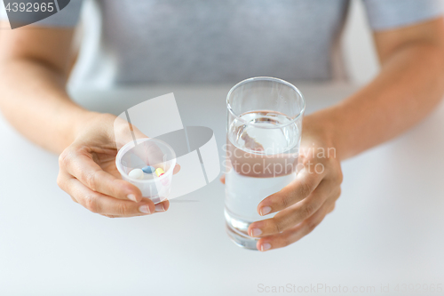 Image of close up of hands with pills and glass of water