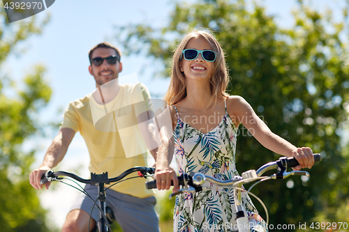 Image of happy young couple riding bicycles in summer