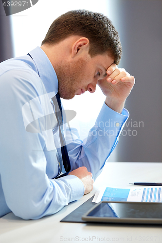 Image of stressed businessman with papers at office