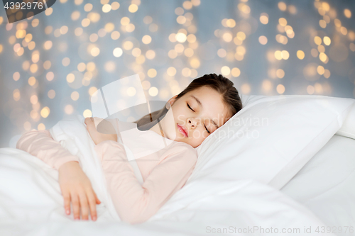 Image of girl sleeping in bed over holidays lights