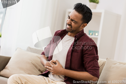 Image of unhappy man suffering from stomach ache at home