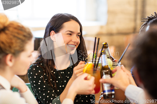 Image of happy friends clinking drinks at bar