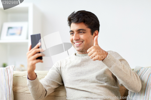 Image of happy man having video call on smartphone at home