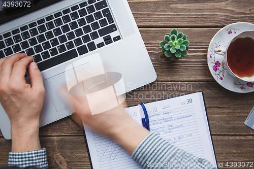 Image of Man working on laptop placed on wooden desk