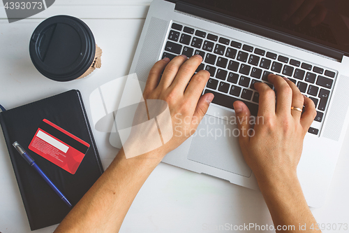 Image of Man working on laptop placed on white desk