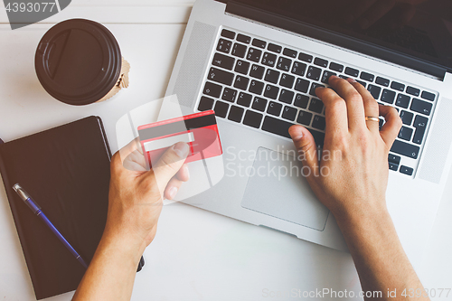 Image of Man working on laptop placed on white desk