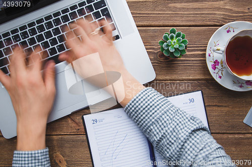 Image of Man working on laptop placed on wooden desk