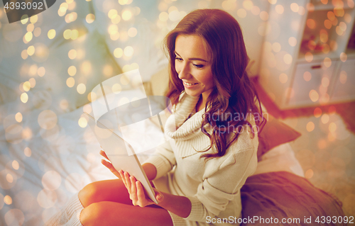 Image of happy young woman with tablet pc in bed at home