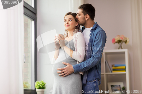 Image of man hugging pregnant woman at window at home