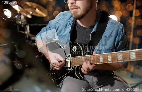 Image of close up of musician playing guitar at studio