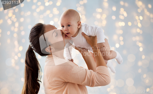 Image of happy mother kissing little baby boy over lights