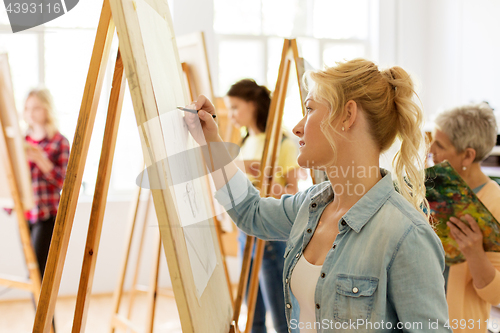 Image of woman with easel drawing at art school studio