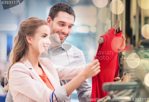 Image of happy young couple choosing dress in mall