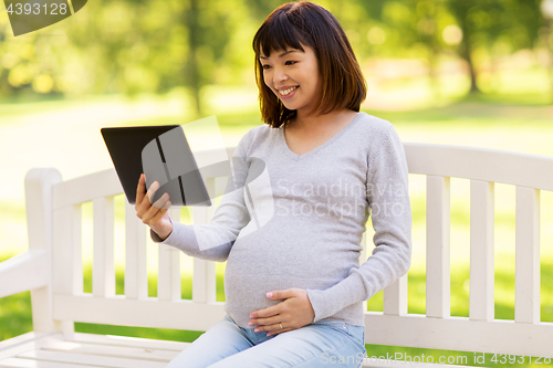 Image of happy pregnant asian woman with tablet pc at park