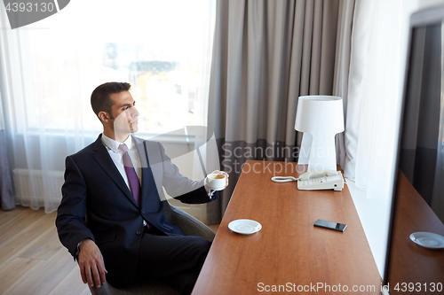 Image of businessman drinking coffee at hotel room