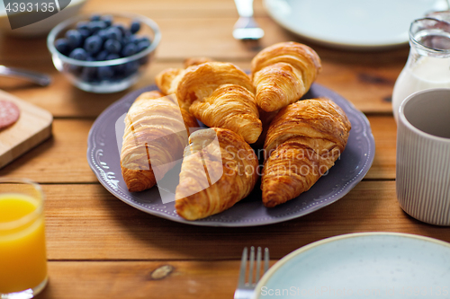 Image of plate of croissants on wooden table at breakfast