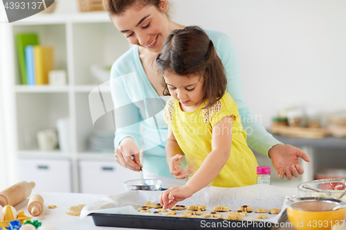 Image of happy mother and daughter making cookies at home