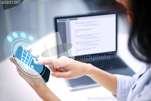 Image of close up of woman with shopping cart on smartphone