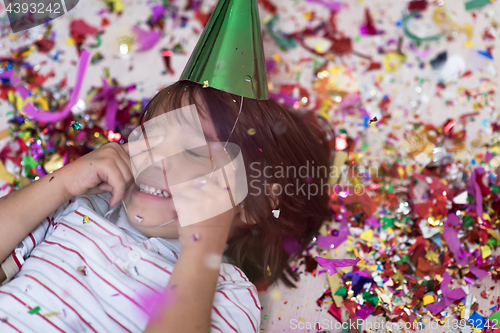 Image of kid blowing confetti while lying on the floor