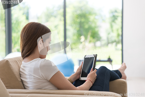 Image of woman sitting on sofa with tablet computer