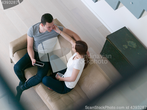 Image of couple relaxing at  home with tablet computers