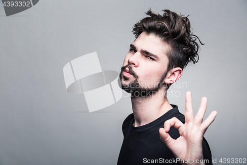 Image of Young man in  black T-shirt shows gesture ok