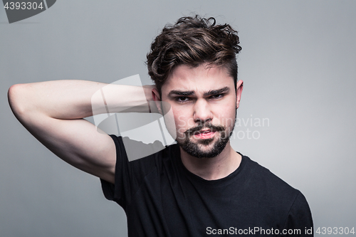 Image of Young handsome man doubting on gray background 