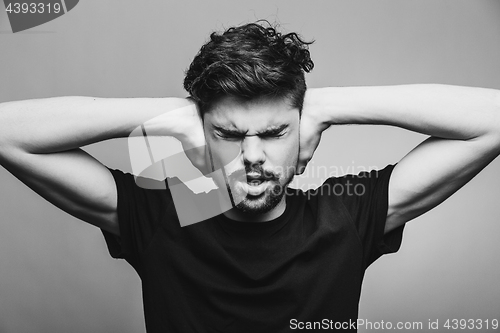 Image of I need silence. Frustrated young man in shirt 