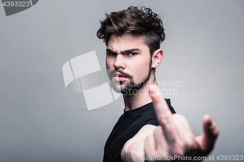 Image of Young man in  black T-shirt showing middle finger