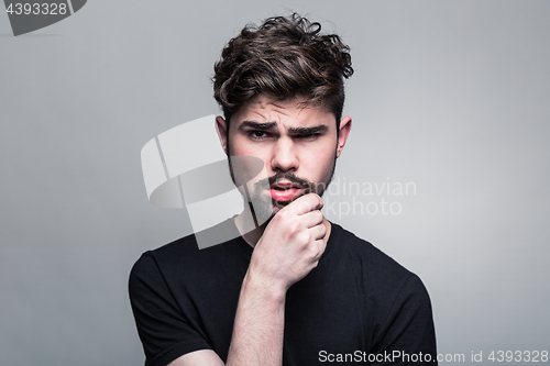 Image of Young handsome man doubting on gray background 