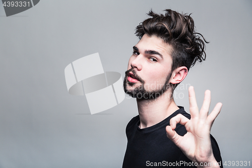 Image of Young man in  black T-shirt shows gesture ok