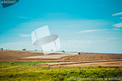 Image of combine harvester on wheat field with  blue sky