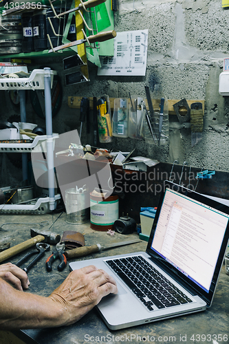 Image of Unrecognizable mechanic working on laptop in garage