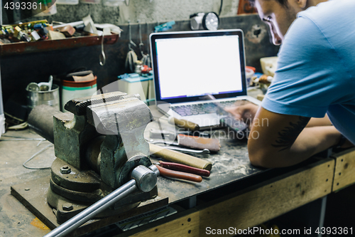 Image of Young man at workshop using mobile phone