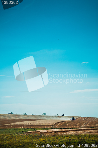 Image of combine harvester on wheat field with  blue sky