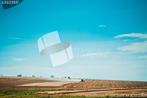 Image of combine harvester on wheat field with  blue sky