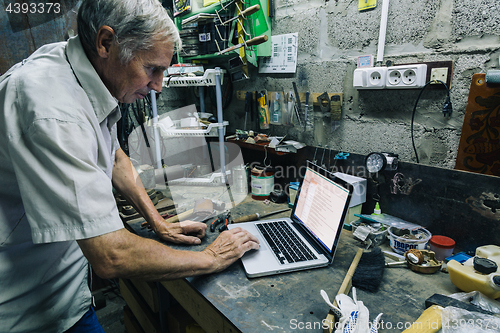 Image of Senior man using laptop at workplace