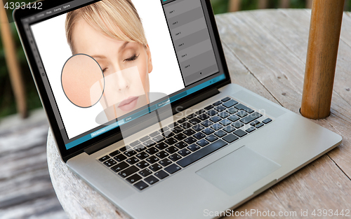 Image of laptop with woman face retouch in graphics editor