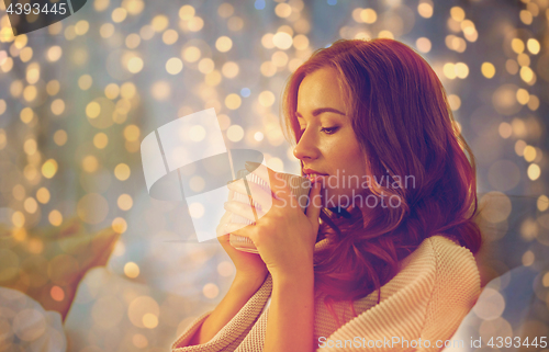 Image of happy woman with cup of coffee in bed at home