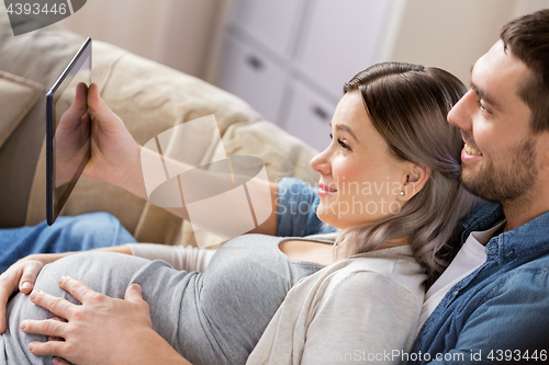 Image of man and pregnant woman with tablet pc at home