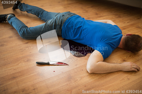 Image of dead man body lying on floor at crime scene