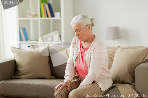 Image of senior woman suffering from pain in leg at home