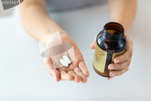 Image of close up of hands holding medicine pills and jar