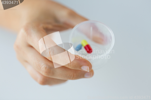 Image of close up of female hand with pills in medicine cup