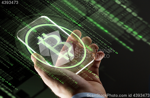 Image of close up of hands with smartphone and bitcoin