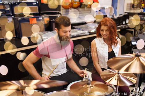 Image of happy man and woman playing cymbals at music store