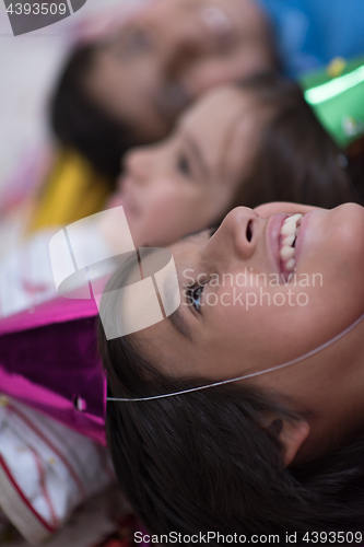 Image of kids  blowing confetti while lying on the floor