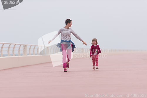 Image of mother and cute little girl on the promenade by the sea